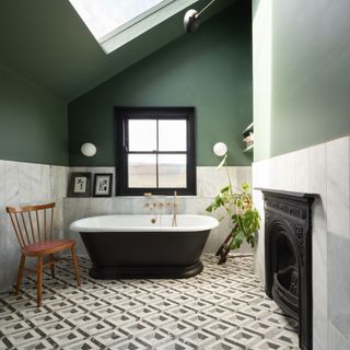 Black and white cast stone bath in tiled bathroom with green walls