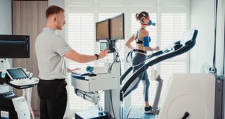 Woman running on treadmill during fitness test being conducted by sports scientist