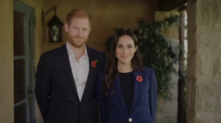 Prince Harry and Meghan Markle wearing blue blazers and smiling