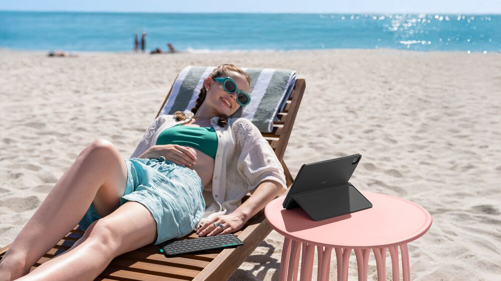 A woman using the Logitech Flip Folio iPad case to prop her iPad up at the beach