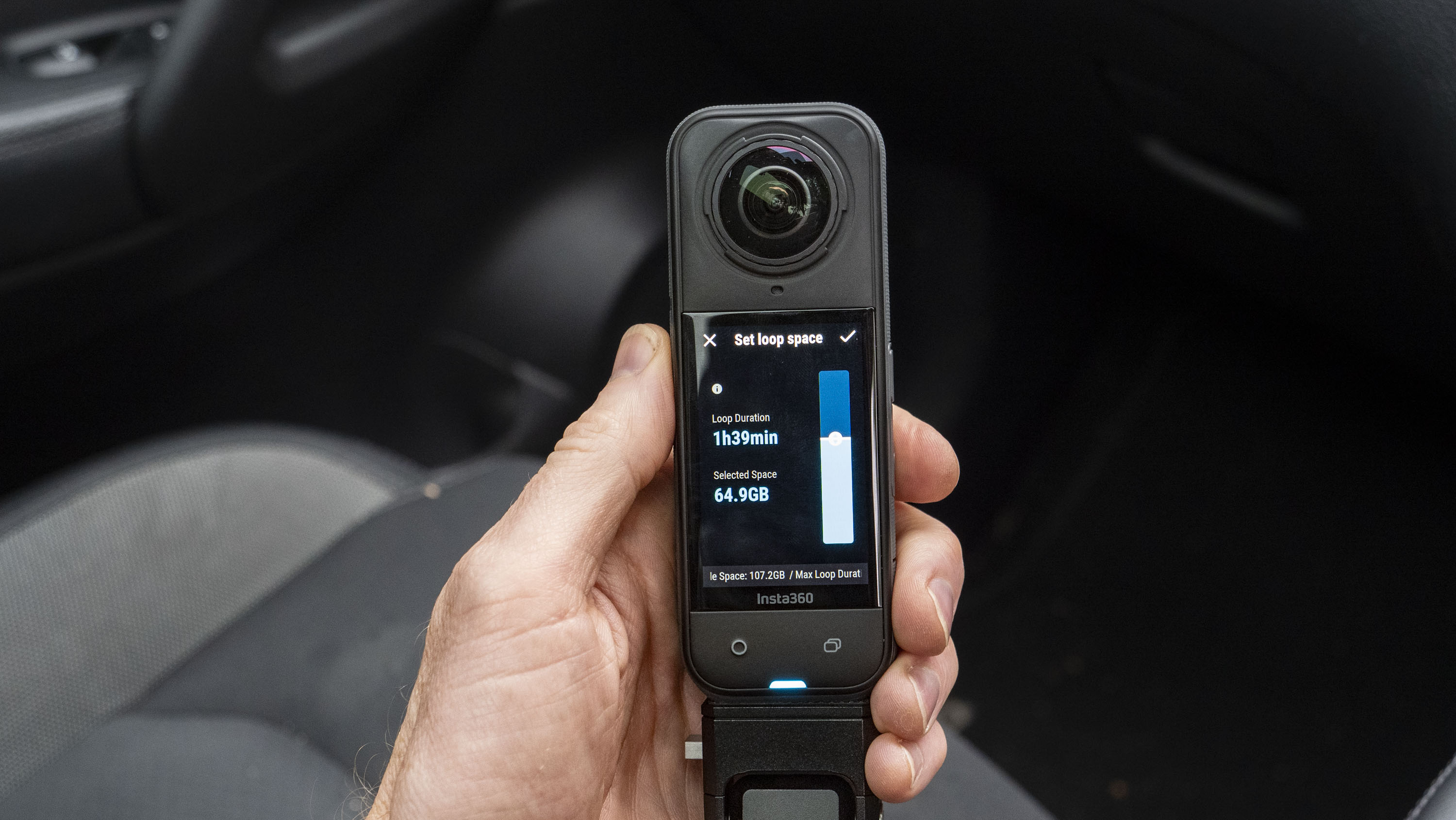 Insta360 X5 inside a car in user's hand, with loop recording options on the display