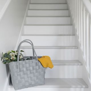 painted hallway staircase with a grey bag of flowers