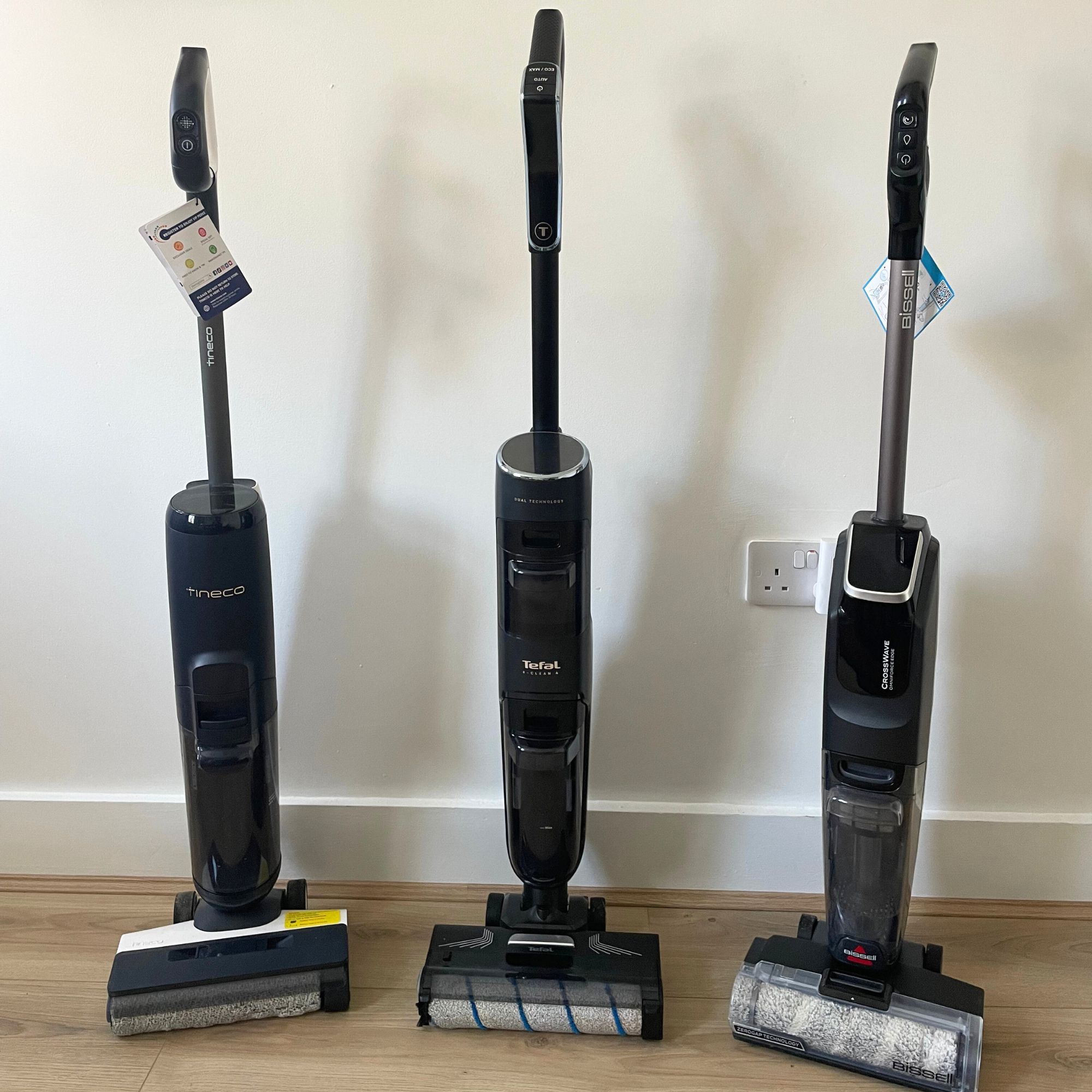 Three vacuum mops standing next to each other on wooden floor