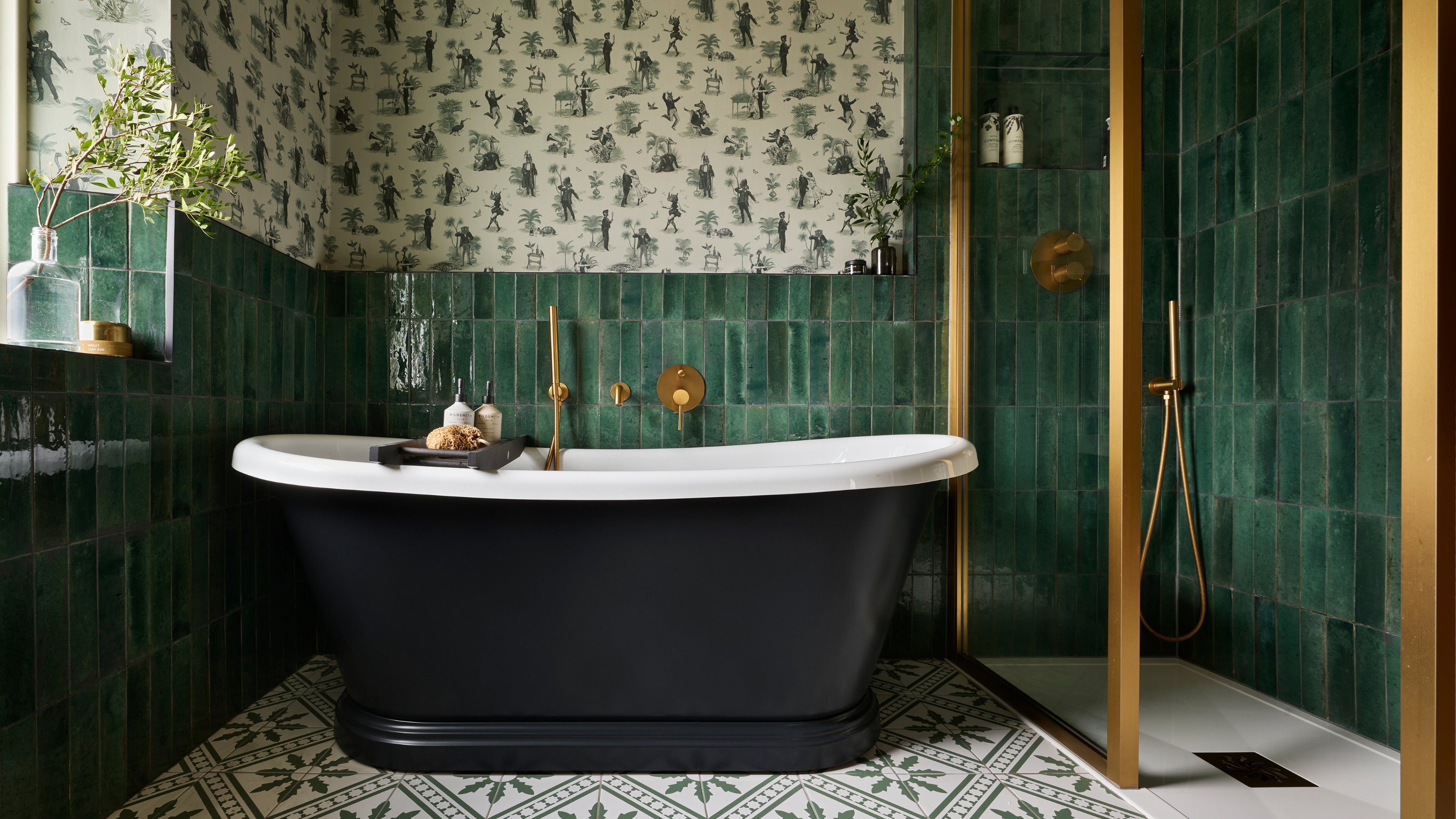 a green tiled bathroom with black freestanding bath and green patterned heritage wallpaper