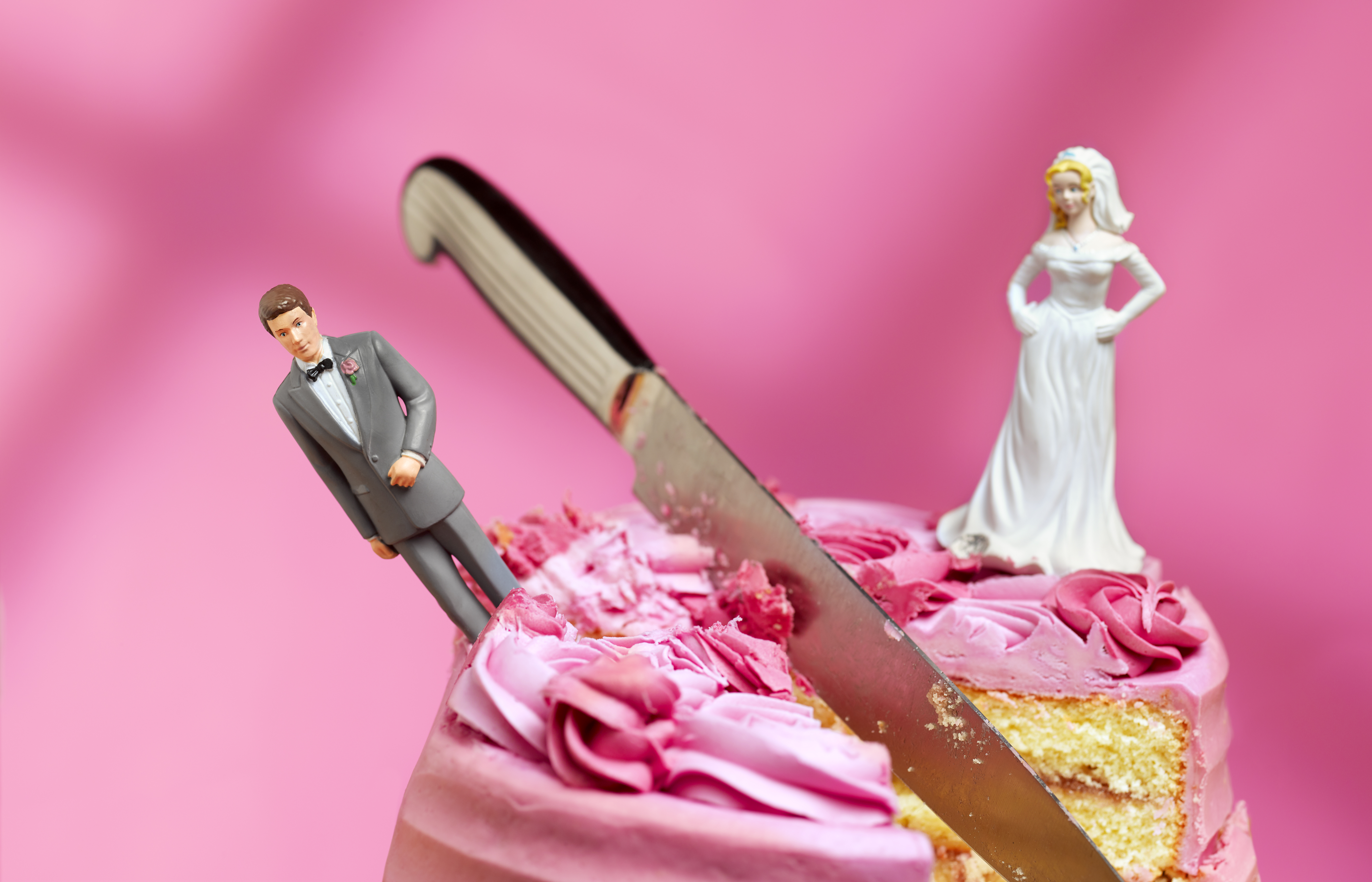 wedding cake being cut with divorced couple on either side