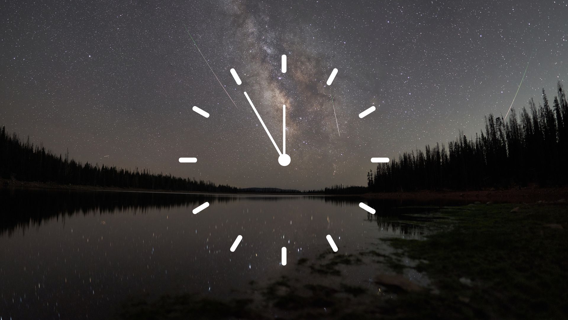 A stylized white clock face is superimposed over a night-time scene, in which meteors race through a starry sky over a lake bordered by the silhouettes of trees. 