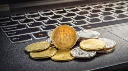 Coins representing cryptocurrency are piled up next to a computer keyboard.