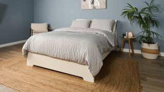 Saatva Classic Luxury Innerspring mattress on a white wooden bed frame in a blue bedroom
