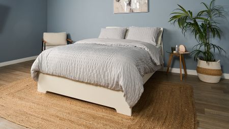 Saatva Classic Luxury Innerspring mattress on a white wooden bed frame in a blue bedroom
