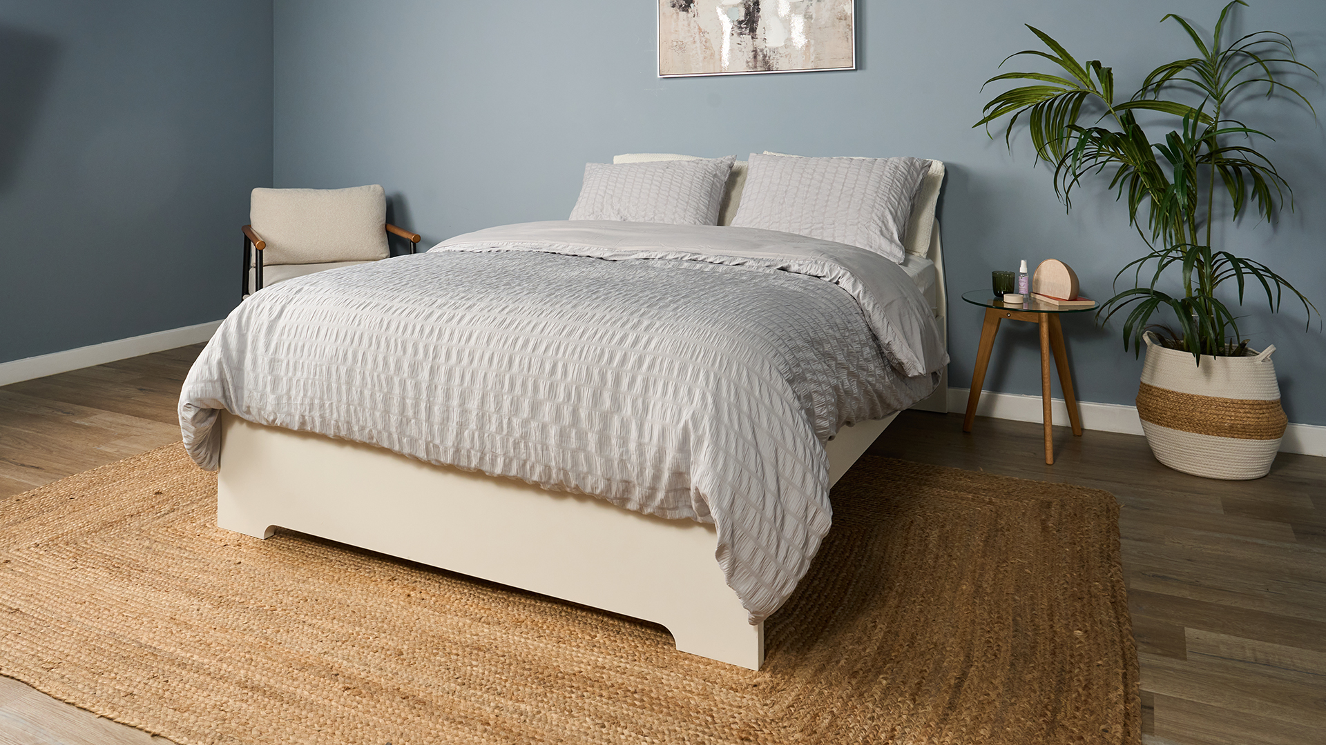 Saatva Classic Luxury Innerspring mattress on a white wooden bed frame in a blue bedroom