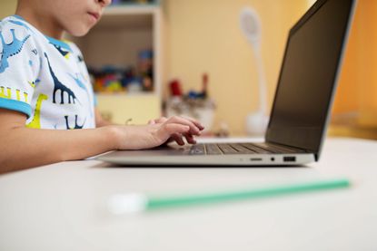 small boy on laptop in bedroom during homeschooling