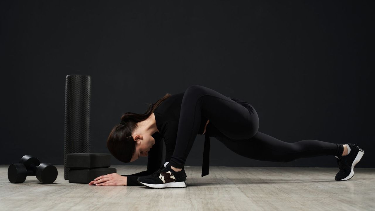 Woman works out beside dumbbells and yoga blocks