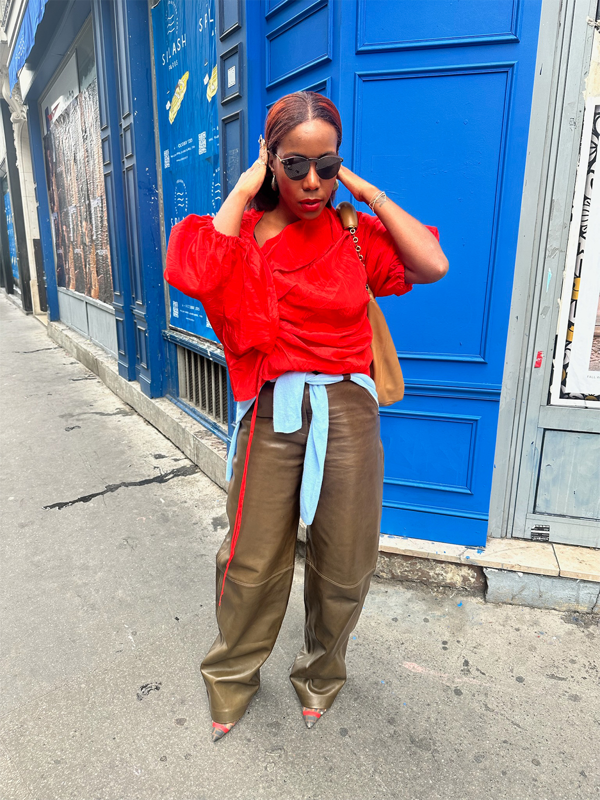 Tiffany Reid wearing a red top and brown leather pants during fashion month.