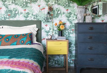 A bedroom with a heavily patterned wallpaper