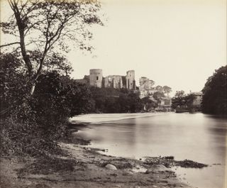 Black and white image of a large castle overlooking a river