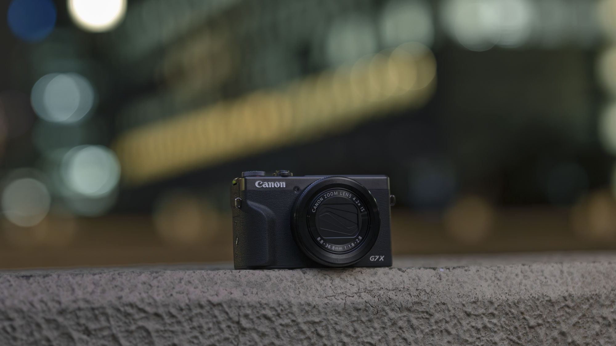 Canon PowerShot G7 X Mark III Anniversary Edition in graphite, on a wall in an urban place at night