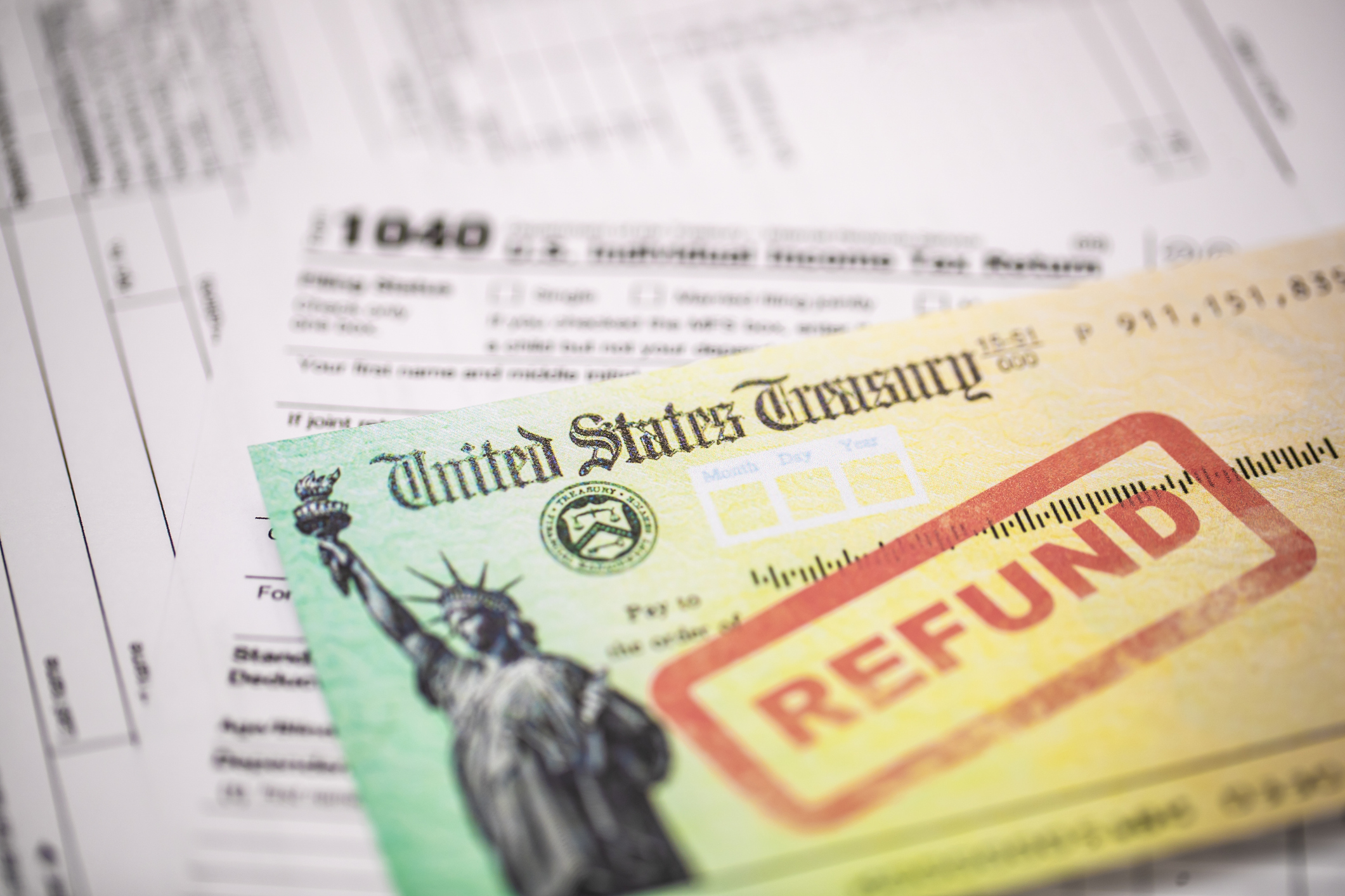 U.S. Treasury check with "Refund" stamped on it on top of a Form 1040