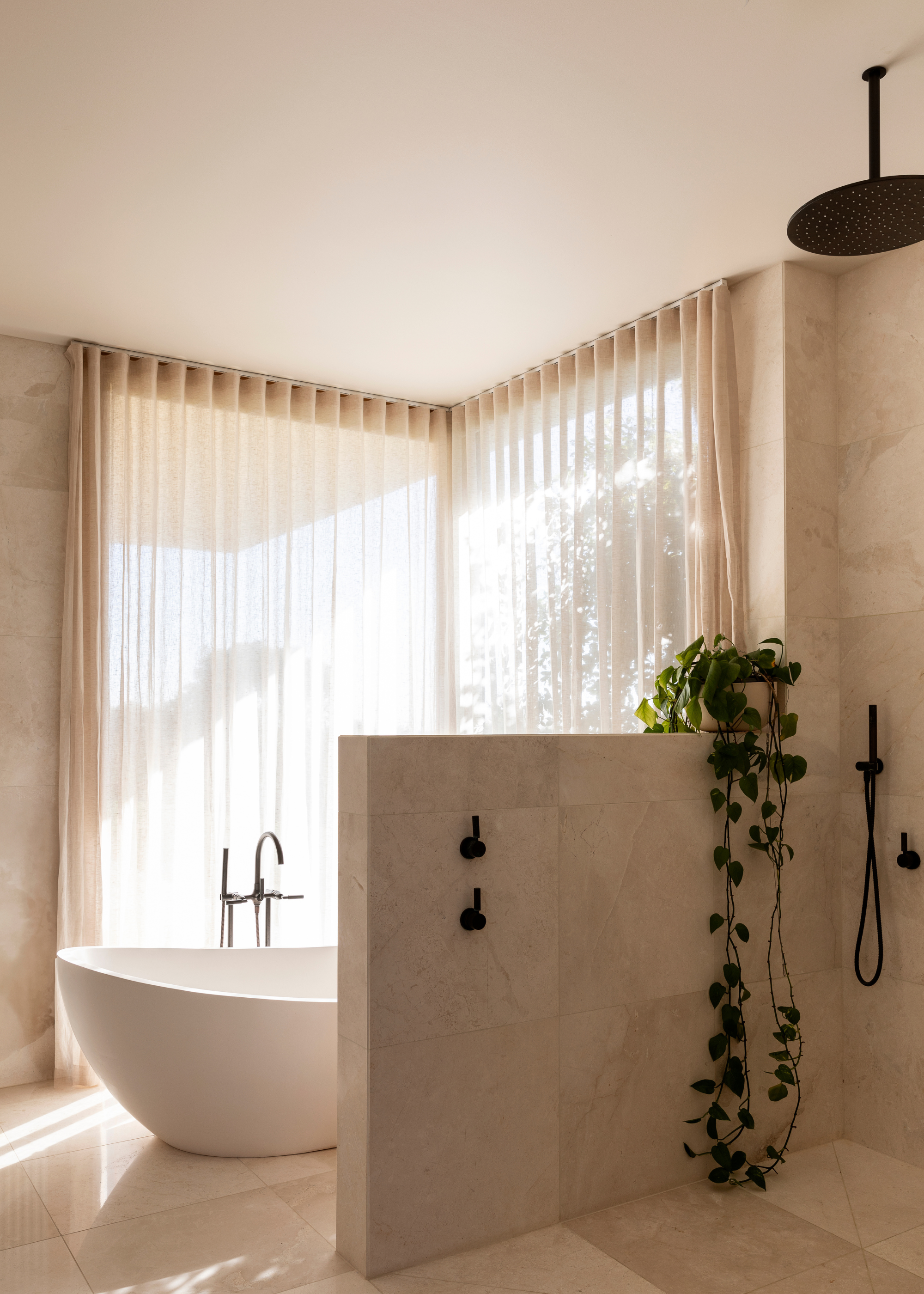 A minimalist stone bathroom, a shower space, a bath tub, and sheer window treatments
