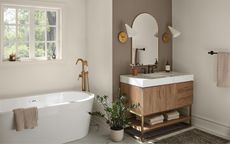 bathroom in off white with darker feature wall, wood vanity, and white tub