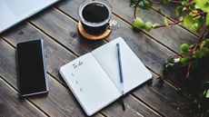 Layout of business tools for demonstrating a business concept with to do list on a wooden background. A laptop, a notebook, a pen, a phone, and a cup of black coffee.