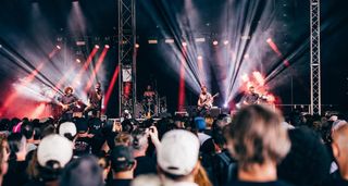 A crowd's eye view of the ArcTanGent Festival 2024 stage as Rabea Massaad's Vower plays, the stage lit in red and white