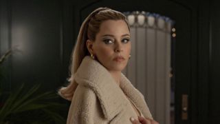 Lindy looking back wearing a fuzzy tan jacket in The Miniature Wife premiere