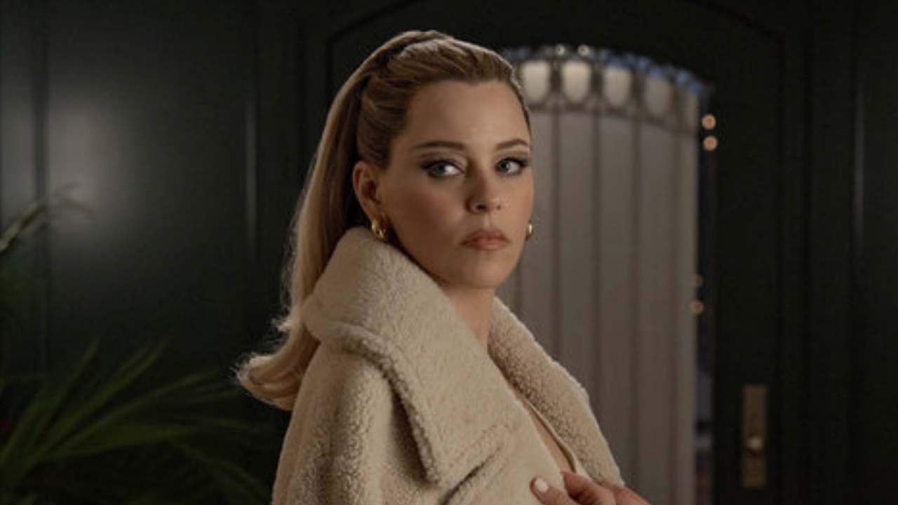 Lindy looking back wearing a fuzzy tan jacket in The Miniature Wife premiere