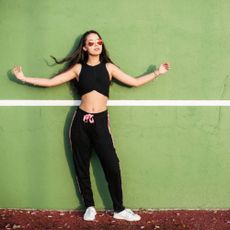 Woman posing in front of a green wall wearing athletic clothing