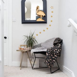 landing with a metal chair, a side table, yellow stars in a pattern on the wall, and a mirror with a flamingo light