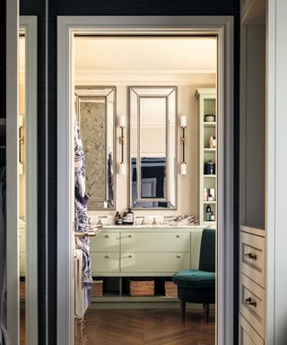 view through bedroom into bathroom with green cabinety and tall silver mirrors