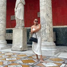 Jasmine Fox-Suliaman wearing a white slip dress, mesh ballet flats, and a black Freja shoulder bag at an art museum