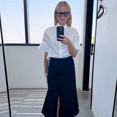 Gwyneth wears a white blouse, black midi skirt, and black Mary Janes.