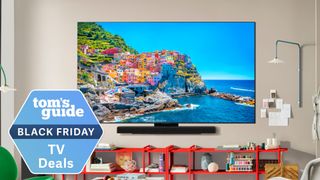 The LG C5 in a wall-mounted position displaying a pastel-colored Italian coastline. Overlaid is a badge that reads: "Tom's Guide Black Friday TV Deals"