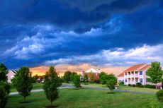 Storm clouds gather over a well-kept neighborhood.