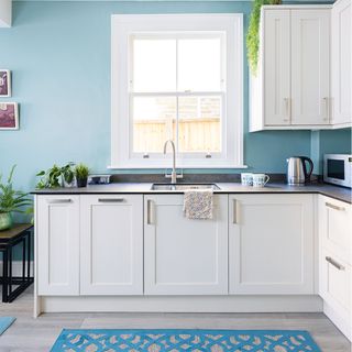 white kitchen with blue walls and black worktops