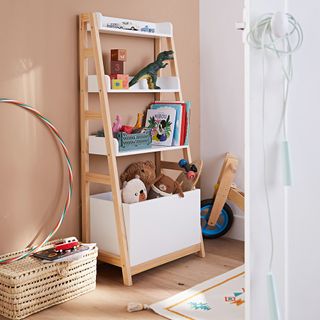 A white storage bookcase in a childrens bedroom with a beige wall