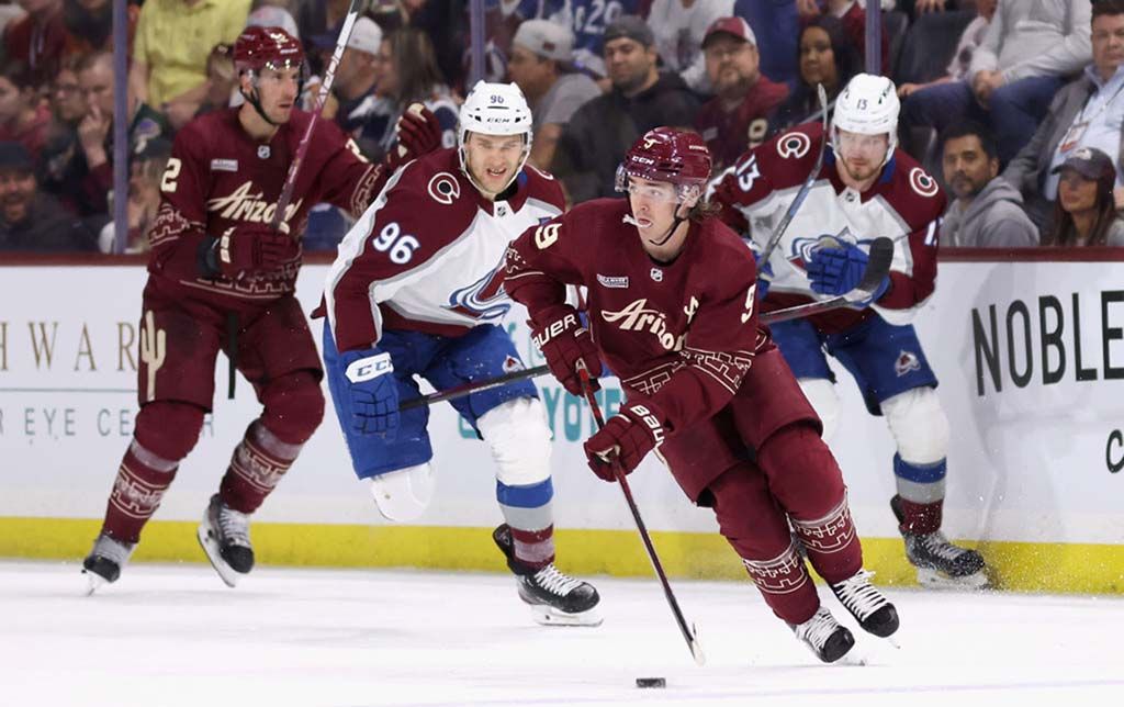 Clayton Keller of the Arizona Coyotes skates with the puck ahead of Mikko Rantanen of the Colorado Avalanche 