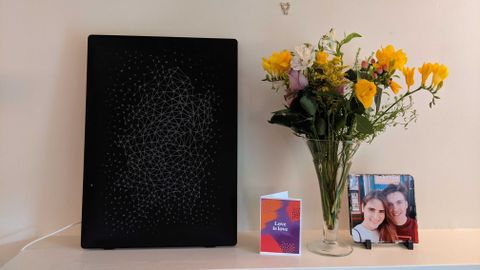 The Symfonisk Picture Frame sat next to a vase of flowers and a card on a mantlepiece