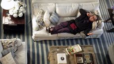 still image from 'Somethings Gotta Give' 2003 movie by nancy meyers showing Jack Nicholson lying on a white linen sofa with a blue stripe carpet underneath, antique furniture and decor and a large hydrangea plant