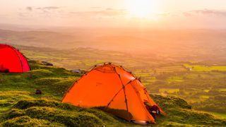 Orange tents on a hill at sunset