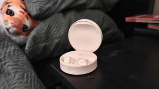 The Fitnexa SomniPods 3 on a bedside tablet, with a stuffed lion examining it.