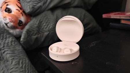 The Fitnexa SomniPods 3 on a bedside tablet, with a stuffed lion examining it.