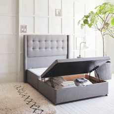 An ottoman storage bed open in a bedroom to reveal the space beneath 