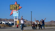 A group of tourists pose in front of the space-age Roy's sign in Amboy, California