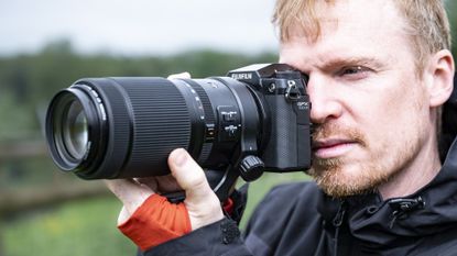 Photographer holding the Fujifilm GFX100S II camera up to their eye