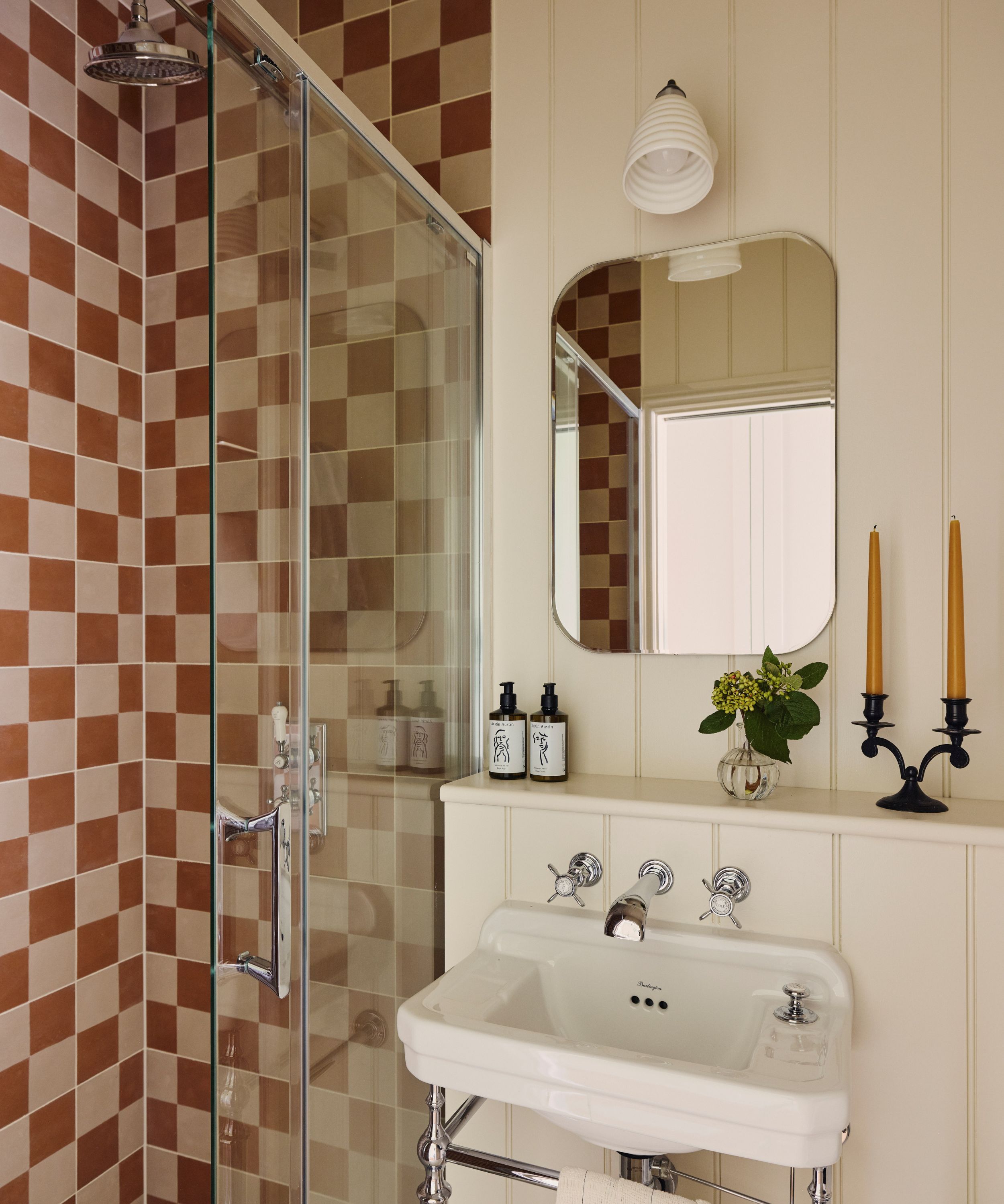 Bathroom with checked tiles in red and pink, the rest of the bathroom in panelled in white