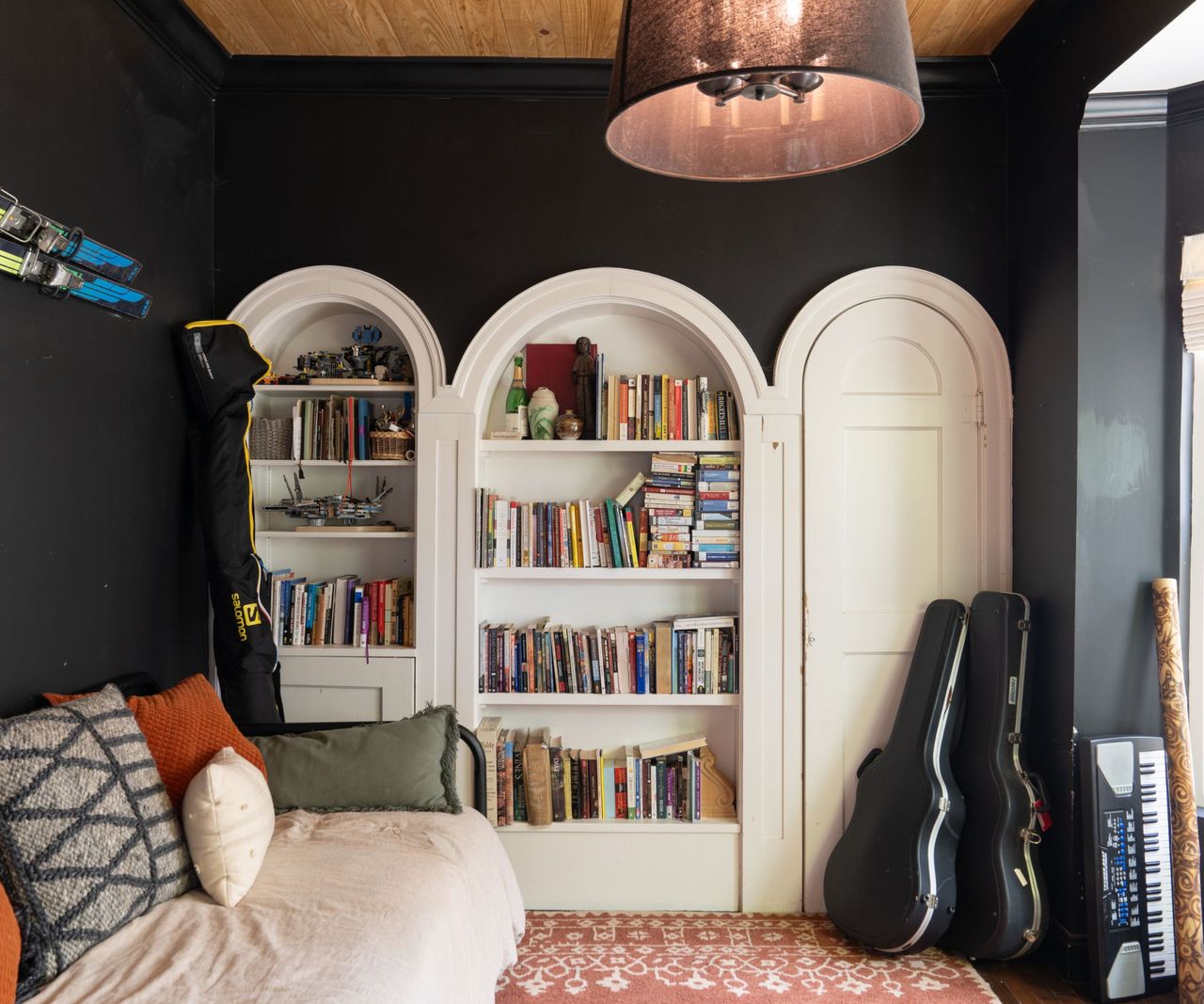 Lounge with black walls, curved bookcases with books and sofa and guitar cases