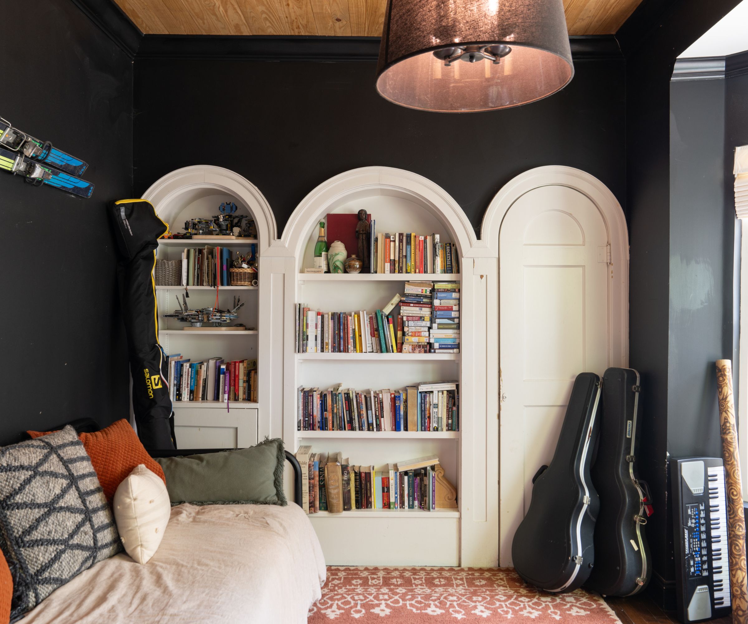 Lounge with black walls, curved bookcases with books and sofa and guitar cases