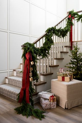 A staircase with a garland, red ribbon and gold bells