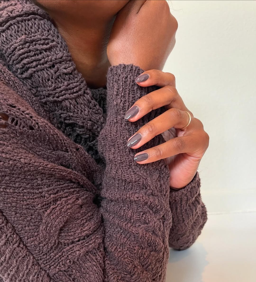 a person wearing brown nail polish and a brown sweater